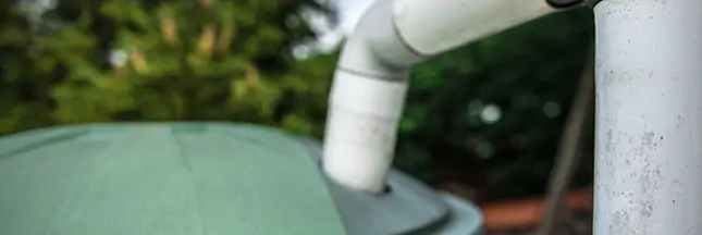Récupérateur d'eau de pluie installé à côté d'une maison